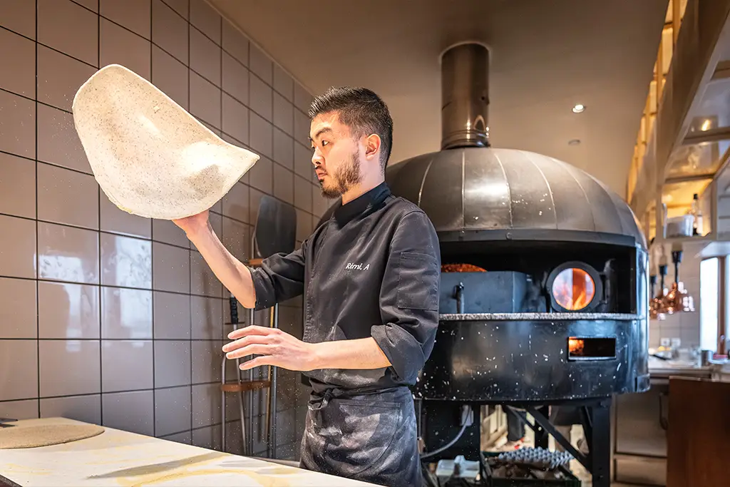 Personne faisant tourner de la pâte à pizza