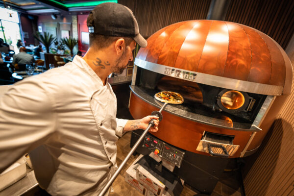 Photo d'une personne mettant une pizza dans une four a pizza Marana