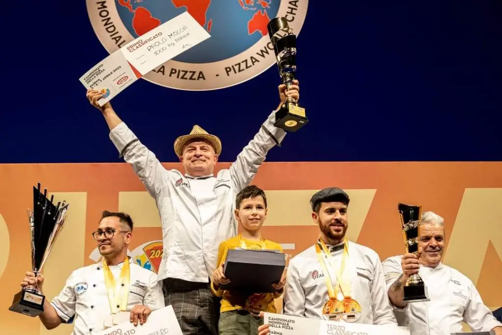 Photo de Paolo Moccia aillant gagner le championnat du monde de la pizza il brandit son trophée d'une main.